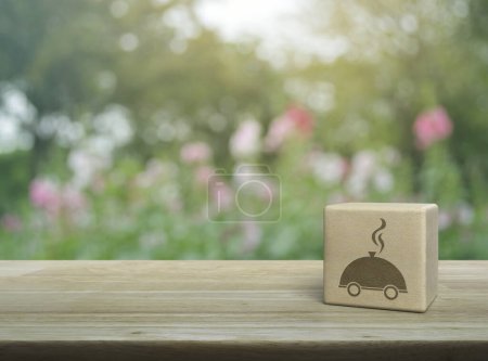 Téléchargez les photos : Icône cloche restaurant sur cube bloc de bois sur table en bois sur flou fleur rose et arbre dans le parc, concept de livraison de nourriture d'affaires en ligne - en image libre de droit
