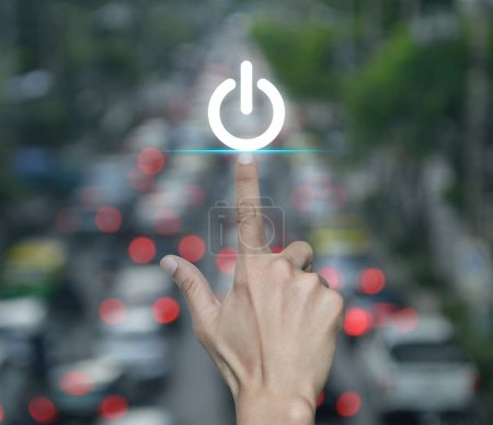 Téléchargez les photos : Main appuyant sur l'icône bouton d'alimentation sur flou de l'heure de pointe avec les voitures et la route en ville, Démarrer concept d'entreprise - en image libre de droit