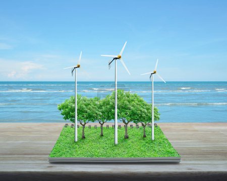 Turbinas eólicas, árboles, hierba y aves de un libro abierto sobre mesa de madera sobre mar tropical y cielo azul con nubes blancas, concepto de Ecología Empresarial