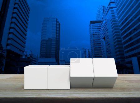 Flipping of four white block cubes on wooden table over modern office city tower and skyscraper