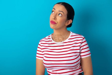 Photo for Woman wearing striped T-shirt , looks pensively aside, plans actions after university, imagines what to do Thinks over about new project. - Royalty Free Image