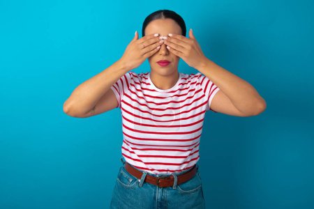 Photo for Woman wearing striped T-shirt covering eyes with both hands, doesn't want to see anything or feeling ashamed. Human feelings reactions. - Royalty Free Image