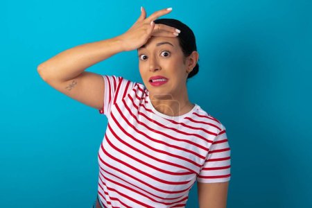 Photo for Oops, what did I do? woman wearing striped T-shirt holding hand on forehead with frightened and regret expression. - Royalty Free Image