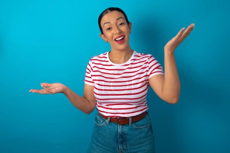 Photo for Cheerful woman wearing striped T-shirt making a welcome gesture raising arms over head. - Royalty Free Image