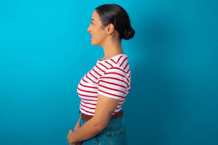 Photo for Profile of smiling woman wearing striped T-shirt with healthy skin, has contemplative expression, ready to have outdoor walk. - Royalty Free Image
