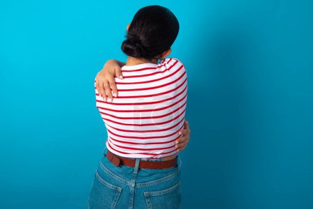 Téléchargez les photos : Femme portant T-shirt rayé s'embrassant heureux et positif à partir de l'arrière. Amour de soi et soin de soi. - en image libre de droit