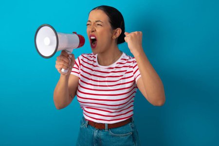 Photo for Woman wearing striped T-shirt communicates shouting loud holding a megaphone, expressing success and positive concept, idea for marketing or sales. - Royalty Free Image