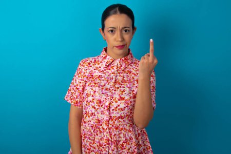 Photo for Woman wearing floral dress shows middle finger bad sign asks not to bother. Provocation and rude attitude. - Royalty Free Image