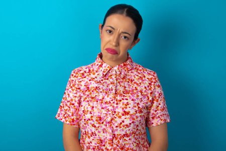 Photo for Woman wearing floral dress over blue studio background depressed and worry for distress, crying angry and afraid. Sad expression. - Royalty Free Image