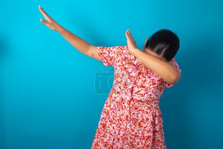 Téléchargez les photos : Photo de femme funky portant une robe florale sur fond bleu studio show disco move dab - en image libre de droit