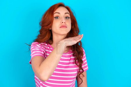 Photo for Redhead woman wearing pink striped T-shirt over blue background cutting throat with hand as knife, threaten aggression with furious violence. - Royalty Free Image