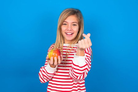 Photo for Teen girl wearing striped shirt over blue background smiling in love showing heart symbol and shape with hands. Romantic concept. - Royalty Free Image