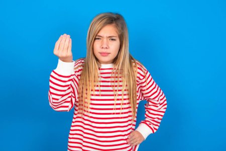 Foto de What the hell are you talking about. Shot of frustrated teen girl wearing striped shirt over blue background gesturing with raised hand doing Italian gesture, frowning, being displeased and confused with dumb question. - Imagen libre de derechos