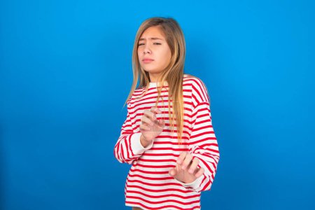 Photo for Ugh how disgusting! Displeased teen girl wearing striped shirt over blue background, has dissatisfied facial expression as sees something abominable. - Royalty Free Image