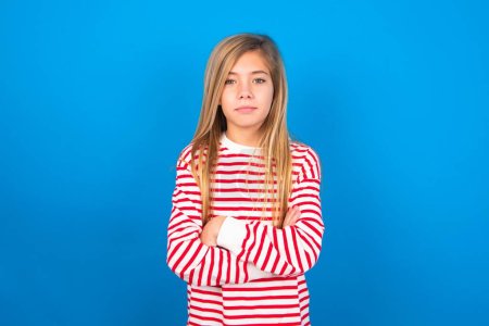 Foto de Imagen de chica adolescente enojada con camisa a rayas sobre fondo azul mirando a la cámara. - Imagen libre de derechos