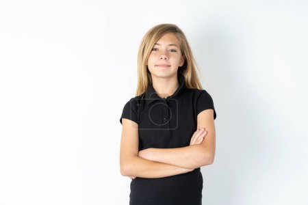 Foto de Soñador relajado hermosa chica adolescente caucásica con vestido negro sobre blanco estudio de fondo cruzando brazos - Imagen libre de derechos