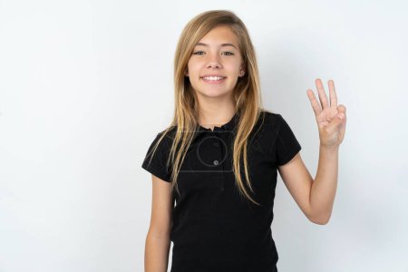 Photo for Beautiful caucasian teen girl wearing black T-shirt over white wall showing and pointing up with fingers number three while smiling confident and happy. - Royalty Free Image