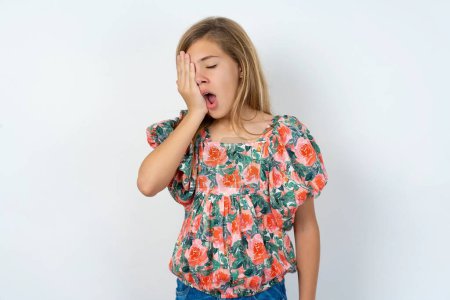 Photo for Beautiful caucasian teen girl wearing flowered blouse over white wall Yawning tired covering half face, eye and mouth with hand. Face hurts in pain. - Royalty Free Image