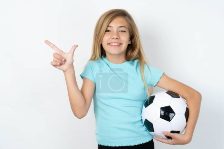 Photo for Beautiful caucasian teen girl wearing sportswear holding a football ball over white wall pointing up with fingers number eight in Chinese sign language. - Royalty Free Image
