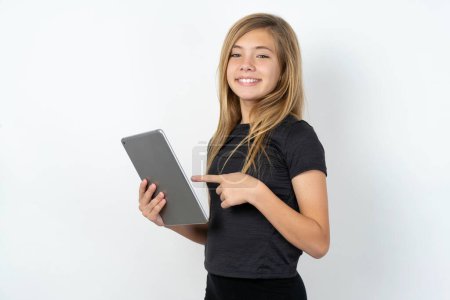 Foto de Foto de alegre chica adolescente caucásica con camiseta negra navegando por Internet con tableta - Imagen libre de derechos