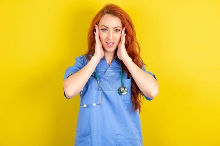 Téléchargez les photos : Jeune femme médecin aux cheveux roux sur fond jaune studio avec agréable regardant gai, Réaction heureuse - en image libre de droit