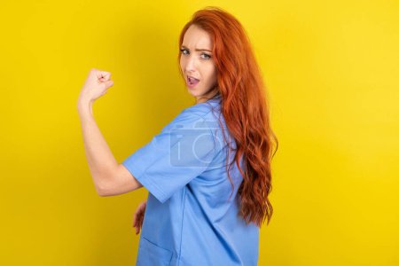 Téléchargez les photos : Profil vue de côté portrait de jeune femme médecin aux cheveux roux sur fond de studio jaune célèbre la victoire - en image libre de droit