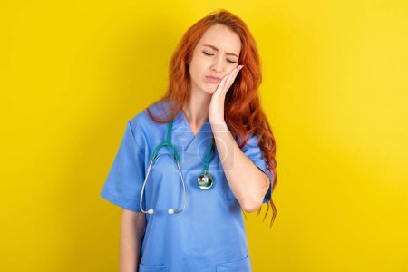 Photo for Young red-haired doctor woman over yellow studio background  with toothache on yellow background - Royalty Free Image