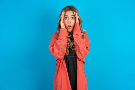 Photo for Young beautiful blonde woman wearing red overshirt with scared expression, keeps hands on head, jaw dropped, has terrific expression. Omg concept - Royalty Free Image