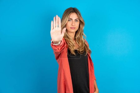 Photo for Blonde woman wearing overshirt  doing stop sing with palm of the hand. Warning expression with negative and serious gesture on the face. - Royalty Free Image