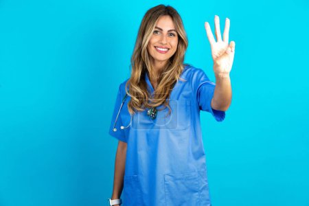 Photo for Beautiful doctor woman standing over blue studio background showing and pointing up with fingers number three while smiling confident and happy. - Royalty Free Image