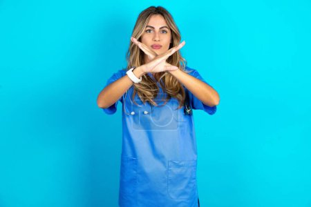 Photo for Beautiful doctor woman standing over blue studio background rejection expression crossing arms doing negative sign, angry face - Royalty Free Image