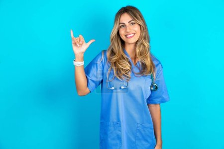 Photo for Beautiful doctor woman standing over blue studio background showing up number six Liu with fingers gesture in sign Chinese language - Royalty Free Image
