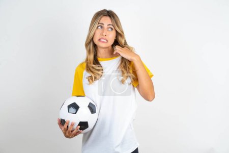 Photo for Young beautiful woman holding football ball over white background stressed, anxious, tired and frustrated, pulling shirt neck, looking frustrated with problem - Royalty Free Image