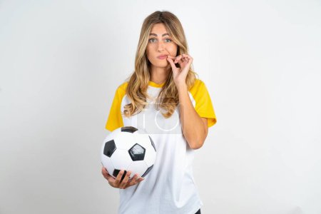 Photo for Disappointed dejected young beautiful woman holding football ball over white background wipes tears stands stressed with gloomy expression. Negative emotion - Royalty Free Image