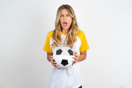 Photo for Young beautiful woman holding football ball over white background yawns with opened mouth stands. Daily morning routine - Royalty Free Image