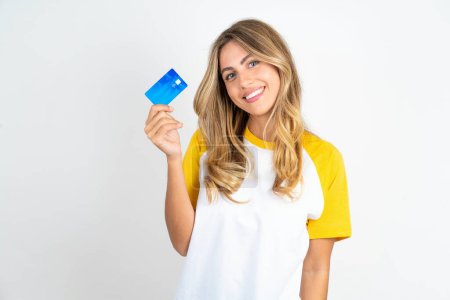 Téléchargez les photos : Gros plan photo de belle femme optimiste portant T-shirt de football sur fond blanc tenir carte de crédit - en image libre de droit
