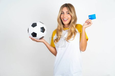 Photo for Photo of happy cheerful smiling positive Young beautiful woman holding football ball over white background recommend credit card holding soccer ball - Royalty Free Image