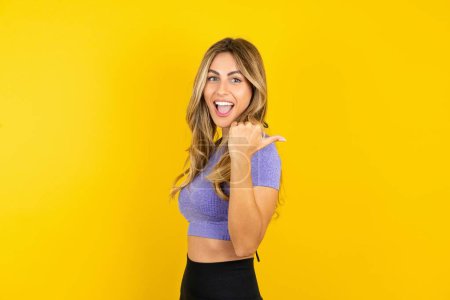Téléchargez les photos : Impressionnante jeune femme portant des vêtements de sport sur fond jaune studio points retour à l'espace vide - en image libre de droit