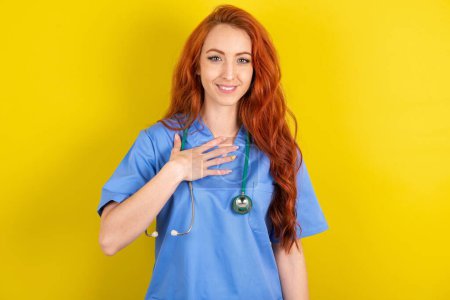 Photo for Young red-haired doctor woman smiles toothily cannot believe eyes expresses good emotions and surprisement - Royalty Free Image