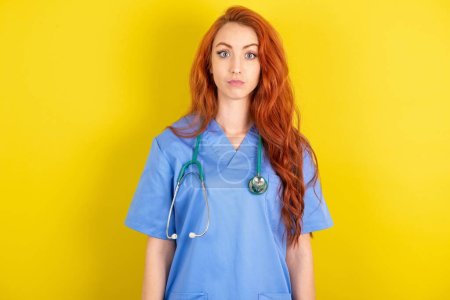 Stunned young red-haired doctor woman stares reacts on shocking news. Astonished MODEL holds breath