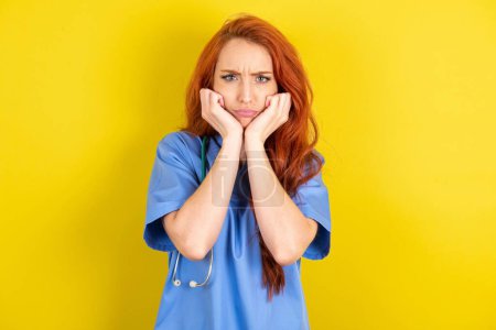 Photo for Portrait of sad young red-haired doctor woman hands face - Royalty Free Image