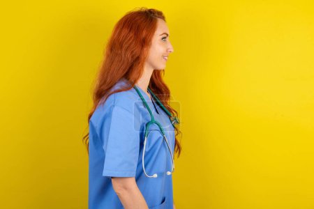Téléchargez les photos : Profil portrait de jeune femme médecin aux cheveux roux regarder espace vide sourire - en image libre de droit