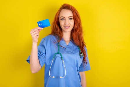 Photo for Photo of happy cheerful young red-haired doctor woman recommend credit card - Royalty Free Image