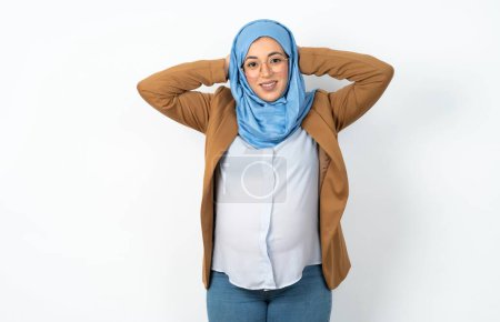 Photo for Satisfied muslim pregnant woman wearing hijab hold hands behind head relaxing - Royalty Free Image