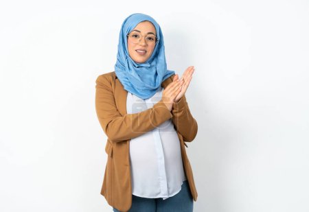 Téléchargez les photos : Musulmane enceinte femme portant hijab applaudissements et applaudissements heureux et joyeux, souriant mains fières ensemble. - en image libre de droit