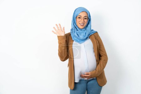 Téléchargez les photos : Musulmane enceinte femme portant hijab Renonciation dire bonjour heureux et souriant, geste de bienvenue amical. - en image libre de droit