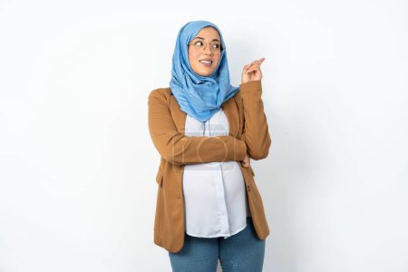 Foto de Foto de atractiva mujer musulmana embarazada usando hijab dedo directo espacio vacío odontología barata - Imagen libre de derechos