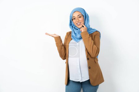 Foto de Divertido musulmán embarazada mujer usando hijab mantenga abierta la palma nuevo producto gran propuesta - Imagen libre de derechos