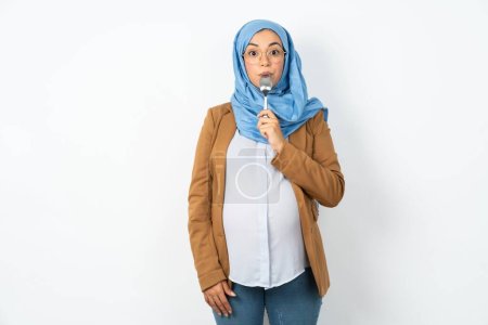 Photo for Very hungry muslim pregnant woman wearing hijab holding spoon into mouth dream of tasty meal - Royalty Free Image