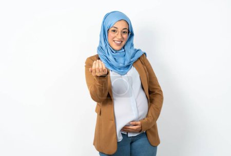 Téléchargez les photos : Femme enceinte musulmane portant hijab invitant à venir avec la main. Heureux que tu sois venu - en image libre de droit